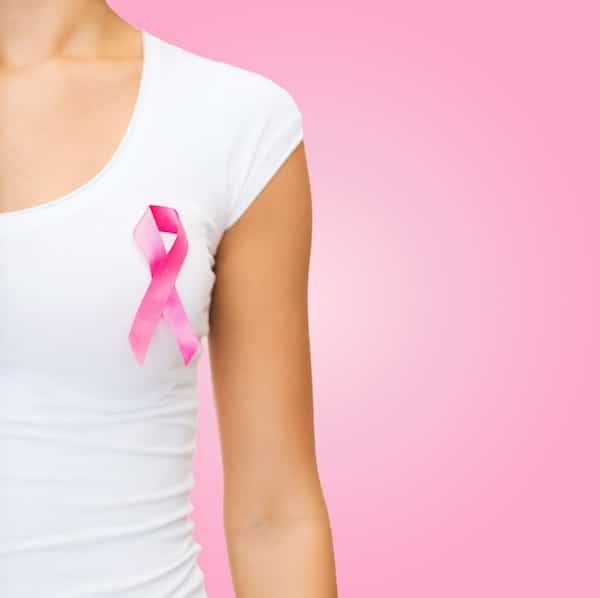 woman in white t-shirt wears a pink breast cancer awareness ribbon