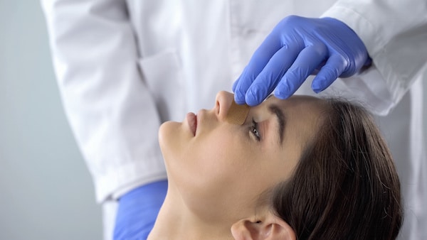 Image of plastic surgeon tending to a woman's rhinoplasty recovery