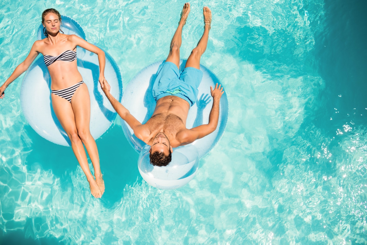 Couple with toned bodies floats in the pool.